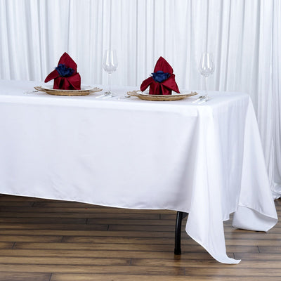 Elegant table setting with red and navy napkins on a white tablecloth.