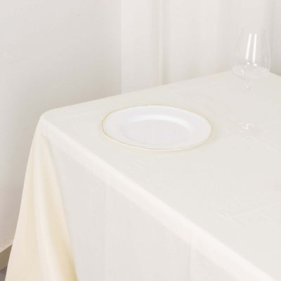 Elegant white plate with gold rim on a cream tablecloth.