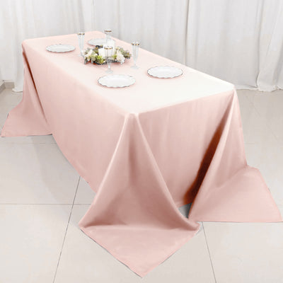 Pink tablecloth draped over a table with plates and floral centerpiece.