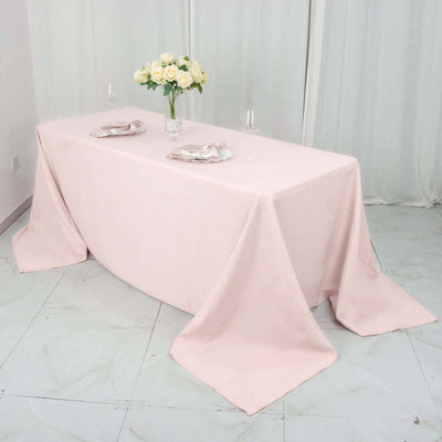 Elegant pink tablecloth draped over a table with floral centerpiece and glassware.