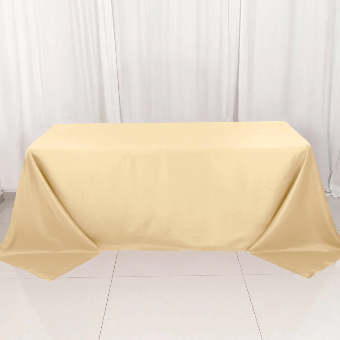 Beige tablecloth draped over a table on a plain backdrop.