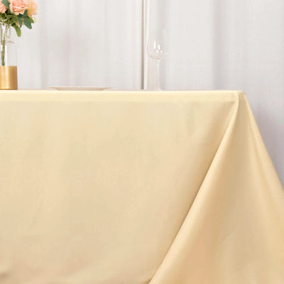 Cream tablecloth draped over a table with a glass and flowers