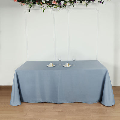 Blue tablecloth draped over a table with plates and glasses on top.