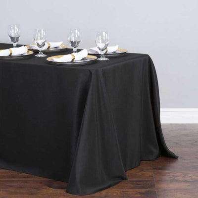 Black tablecloth elegantly draping over a dining table set with glassware and napkins.