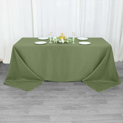 Olive green tablecloth draped over a table with decorative plates and centerpiece.