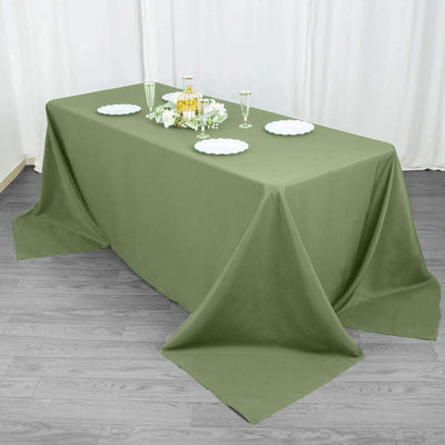 Olive green tablecloth draped over a table with decorative plates and glasses.