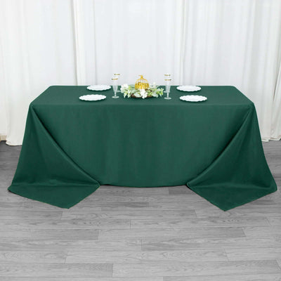 Green tablecloth on a styled table with decorative elements and tableware.