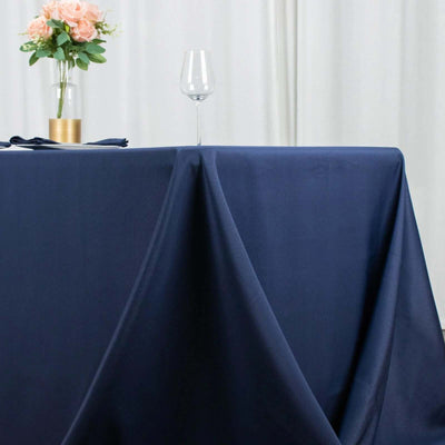 Navy tablecloth draped over a table with a glass and floral centerpiece.
