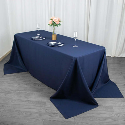 Navy tablecloth draped over a table set with plates and glasses, with flowers in a vase.