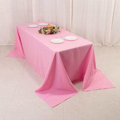 Pink tablecloth draped over a table set for a celebration with floral centerpiece.