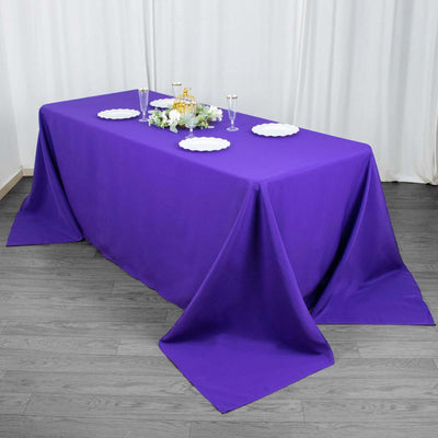 Purple tablecloth draped elegantly over a table with decorative plates and flowers.