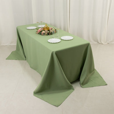 Green tablecloth draped over a table set with plates and floral decor.