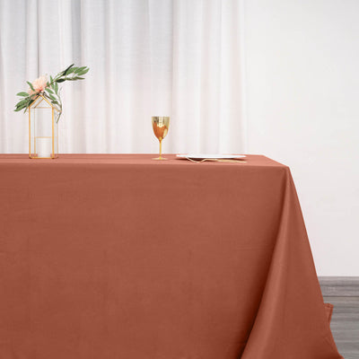 Elegant rust tablecloth on a styled table with gold accents and floral decor.