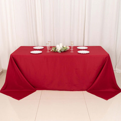 Red tablecloth draped over a table set with plates and decorative elements.