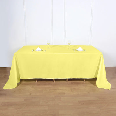 Yellow tablecloth on a dining table set with glasses and cutlery.