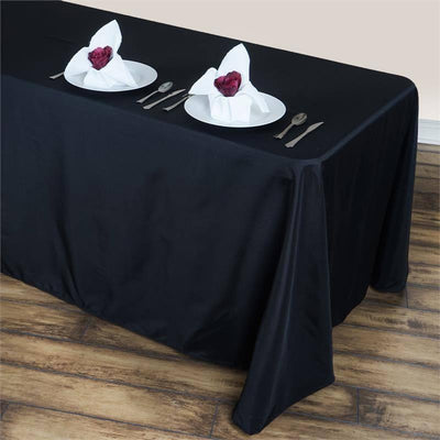 Elegant black tablecloth with neatly arranged plates and folded napkins.