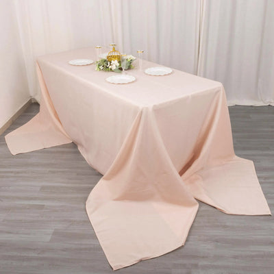 Peach tablecloth draped over a table with decorative plates and floral arrangement.