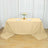 Beige tablecloth draped over a table with plates and a floral centerpiece.