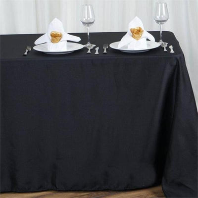 Elegant black tablecloth with decorated napkins and glassware for dining setup.