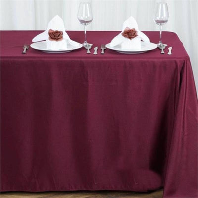 Burgundy tablecloth with white plates and elegant napkin presentation