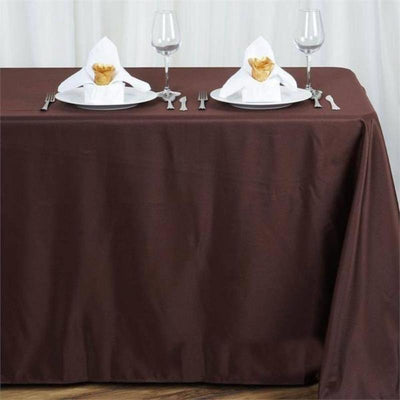 Brown tablecloth set with elegant napkin folds and wine glasses.