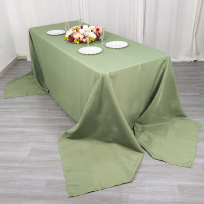 Green tablecloth draped over a dining table with decorative plates and flowers.