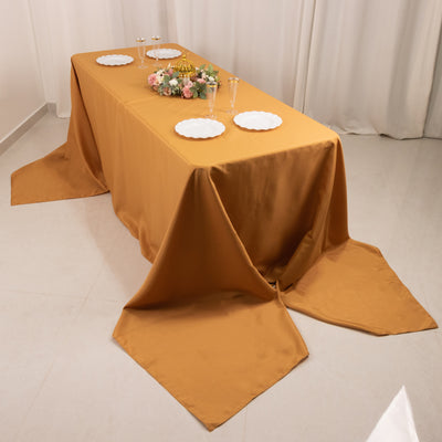 Elegant mustard tablecloth draped over a dining table with plates and floral centerpiece.