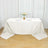 Elegant white table set for dining with floral centerpiece and glassware.