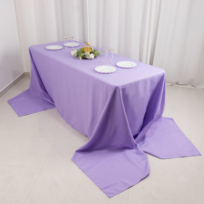 Purple tablecloth draped over a table with white plates and decorative items.