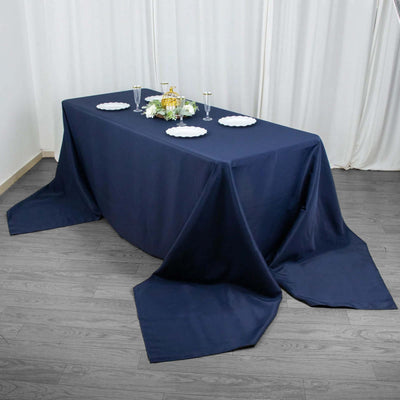 Navy blue tablecloth draped over a table with plates and glasses set for dining.