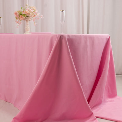 Pink tablecloth draped elegantly over a table with floral centerpiece and glasses.