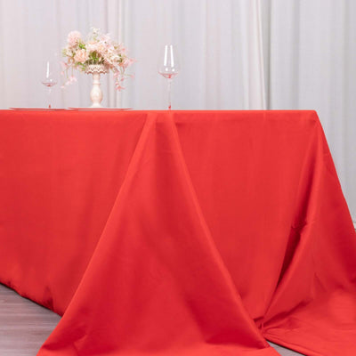 Red tablecloth draped elegantly over a table with floral centerpiece and wine glasses.