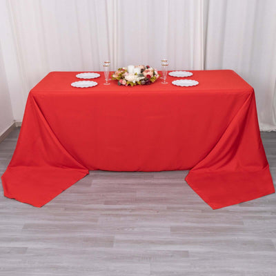 Red tablecloth draped over a table with floral centerpiece and plates.