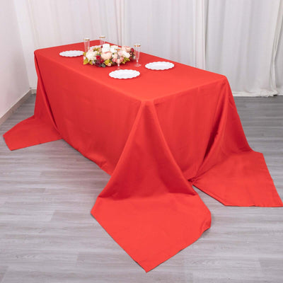 Red tablecloth draped over a table with white plates and floral centerpiece.