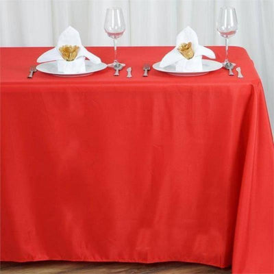 Red tablecloth with elegant napkin folding and glassware set for dining.