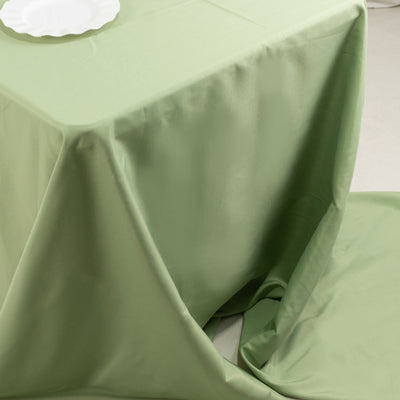 Green tablecloth draped elegantly over a table with a white plate on top.