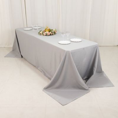 Gray tablecloth draped over a table with floral centerpiece and dinnerware.