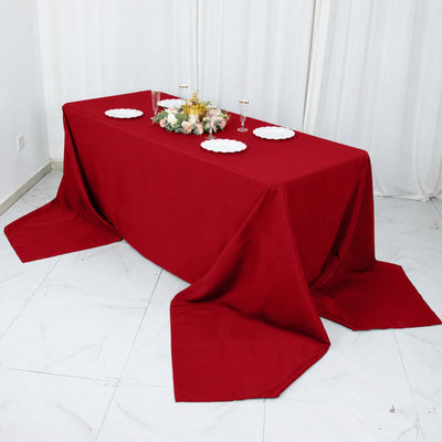 Red tablecloth draped dining table with floral centerpiece and plates
