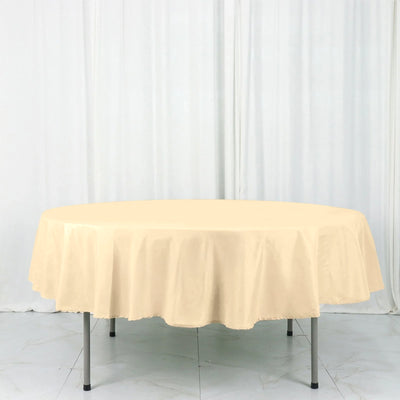Round beige tablecloth draped over a table in a studio setting.