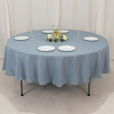 Round blue tablecloth draped on a table set with plates and decorative elements.