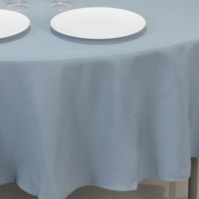 Light blue tablecloth with white plates on a round table.
