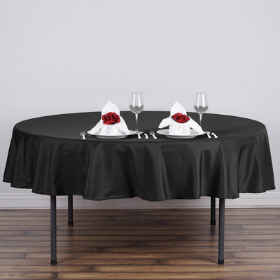 Elegant black tablecloth with white napkins and roses for dining setup.
