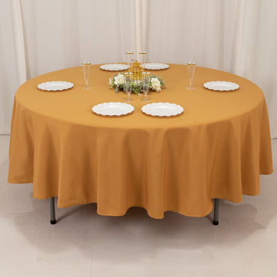 Round mustard tablecloth set for elegant dining with plates and decor.