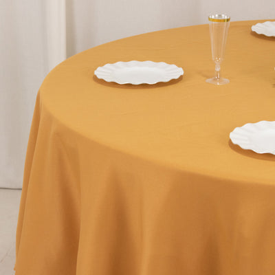 Round mustard yellow tablecloth on a dining table with white plates.