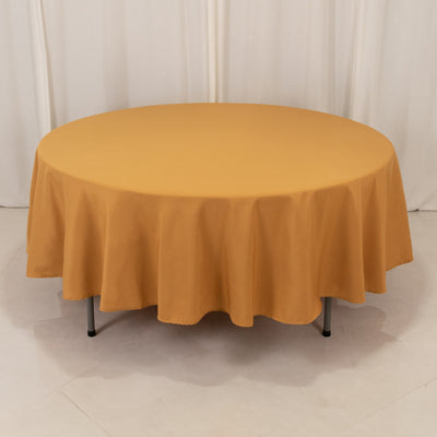 Round orange tablecloth on a round table against a plain backdrop.