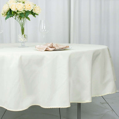 Elegant cream tablecloth draped over a round table with floral centerpiece.