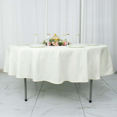 Elegant round table covered with a cream tablecloth and floral centerpiece.