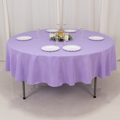 Round purple tablecloth on a table set with white plates and floral centerpiece.