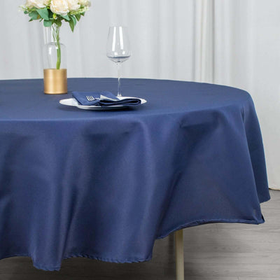 Navy blue tablecloth on a round table with a plate and glass