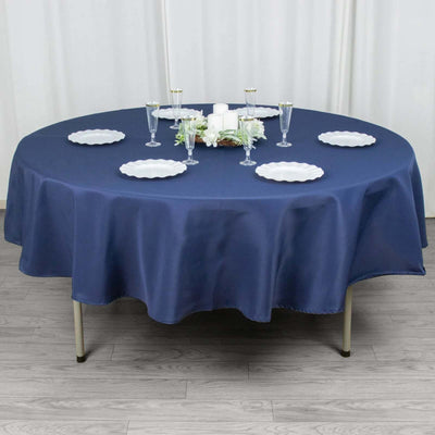 Round navy tablecloth draped over a table with plates and decorative items.